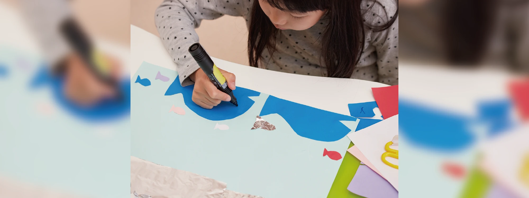 切った紙にペンでデコレーションをしている子供