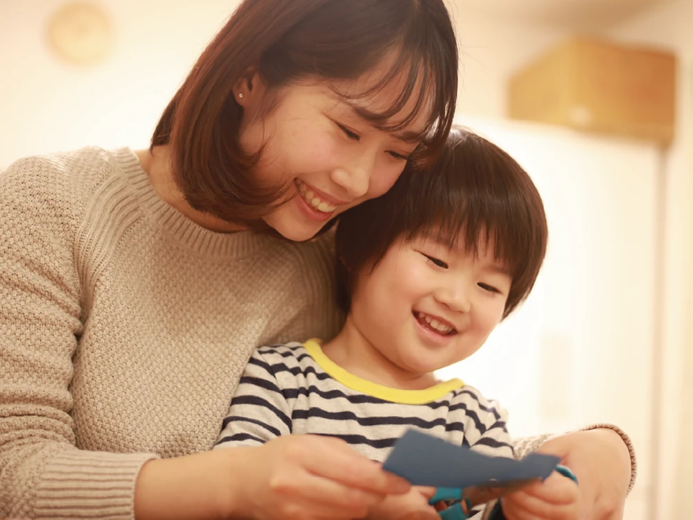 子供とお母さんが一緒に紙をハサミで切っている様子