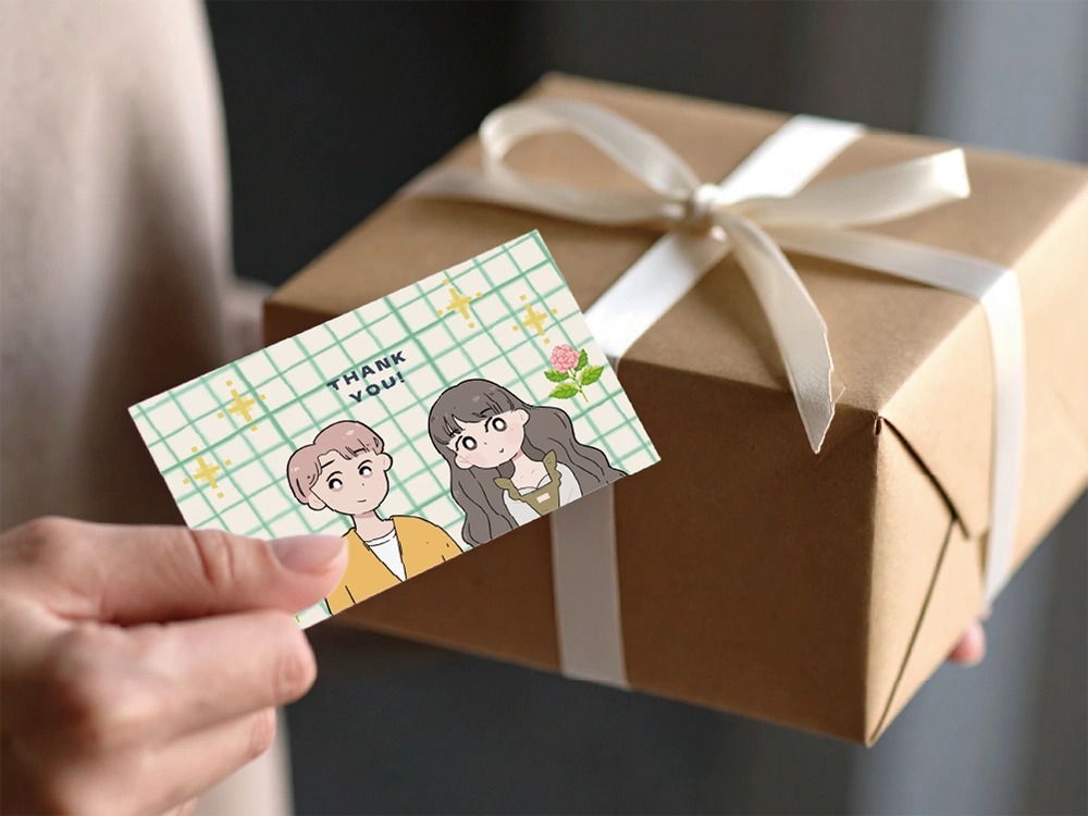 ギフトボックスとキャラクター入りのサンキューカードを手に持つ様子。